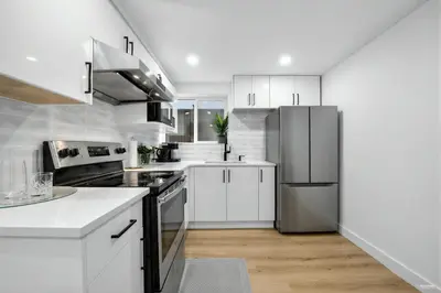a kitchen with white cabinets and a stainless steel refrigerator at Shanaz house in Vancouver