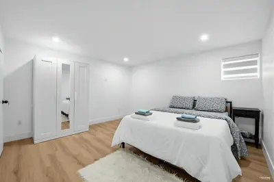 a white bedroom with a bed and a door at Shanaz house in Vancouver