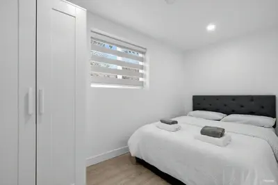a white bedroom with two beds and a window at Shanaz house in Vancouver