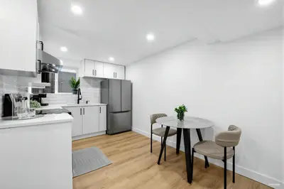 a white kitchen with a table and chairs in it at Shanaz house in Vancouver