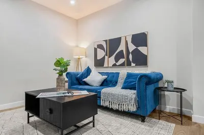 a living room with a blue couch and a table at Herron Rise Luxury 1 Bedroom Basement Suite in Calgary