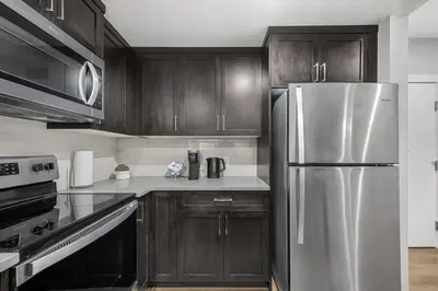 a kitchen with wooden cabinets and a stainless steel refrigerator at Herron Rise Luxury 1 Bedroom Basement Suite in Calgary