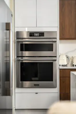 a stainless steel oven in a kitchen with white cabinets at Luxury Haven | Pool | Hot Tub & Sauna |Outdoor BBQ in Calgary