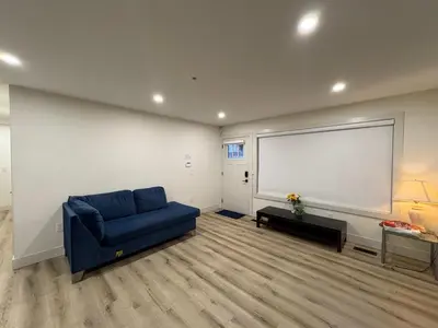 a living room with a blue couch and a large window at Vancouver Downtown Cozy Room - 5-Min Walk to BC Place & Skytrain - Free Parking in Vancouver