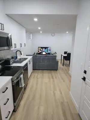 a kitchen and living room with a couch in the background at Mayfair Suite in Airdrie