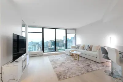 a white living room with a couch and a tv at Luxury High Rise at Gastown Near BC Place in Vancouver