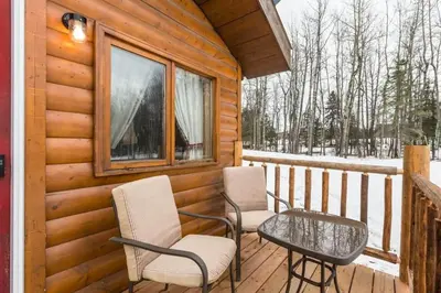 a deck with chairs and a table on a cabin at The White Tail Cabin - Bear Creek Cabins in Winfield