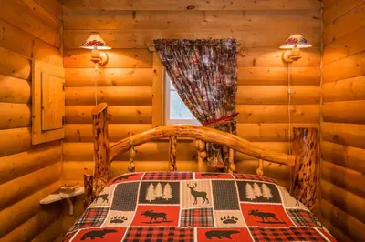 a bedroom with a bed in a log cabin at The White Tail Cabin - Bear Creek Cabins in Winfield