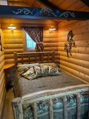 a bedroom with a bed in a log cabin at The Mustang Cabin - Bear Creek Cabins in Winfield