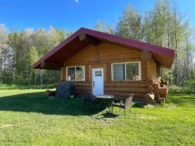 a log cabin with a table and chairs in the grass at The Ram cabin - Bear Creek cabins in Winfield