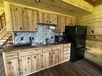 a kitchen with wooden cabinets and a black refrigerator at The Ram cabin - Bear Creek cabins in Winfield