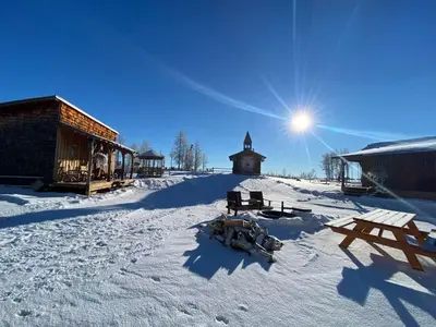 a snow covered ground with a building and a sun at The Lynx cabin - Bear Creek Cabins in Winfield