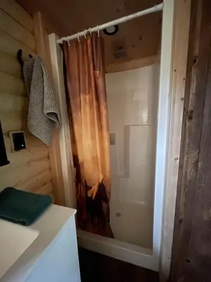 a bathroom with a shower with a shower curtain at The Cowboy cabin - Bear Creek Cabins in Winfield