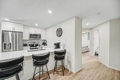 a kitchen with a counter and stools in it at Stylish 2BR Townhome - Near YYC Airport - Free Parking in Calgary