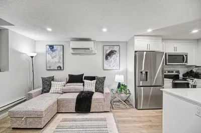 a living room with a couch and a stainless steel refrigerator at Stylish 2BR Townhome - Near YYC Airport - Free Parking in Calgary
