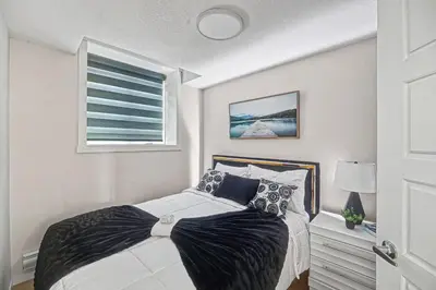 a bedroom with a bed with black and white pillows at Stylish 2BR Townhome - Near YYC Airport - Free Parking in Calgary