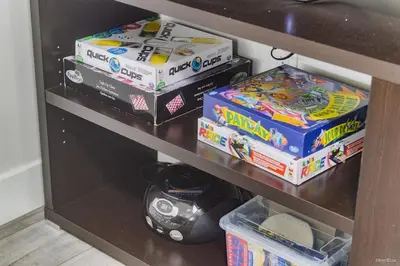 a shelf with boxes of toys and a video game at The Cozy Garden Suite - South Surrey Stay in White Rock