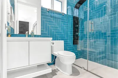 a blue tiled bathroom with a toilet and a sink at Fabulous Modern Home Near Downtown Vancouver in Vancouver