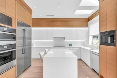 a kitchen with white counters and wooden cabinets at Fabulous Modern Home Near Downtown Vancouver in Vancouver