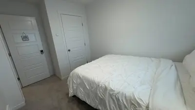 a bedroom with a white bed and two white doors at 3BR Family House in NE Edmonton in Edmonton