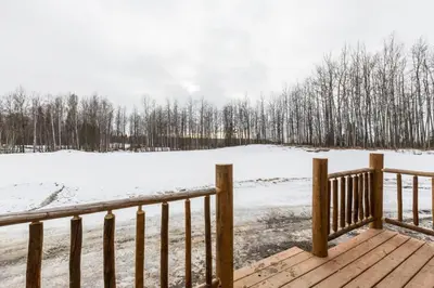 a wooden deck with a snow covered field and trees at The Wolf Cabin - Bear Creek Cabins in Winfield