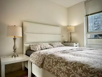 a bedroom with a bed and two lamps and a window at Pleasant and convenient 1B1B close to Richmond Center in Richmond