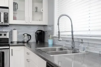 a kitchen with a stainless steel sink and white cabinets at Spacious One Bedroom Queen Bed Inner City Stay in Calgary