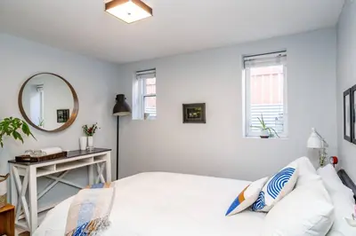 a bedroom with a bed with a mirror and a table at Spacious One Bedroom Queen Bed Inner City Stay in Calgary