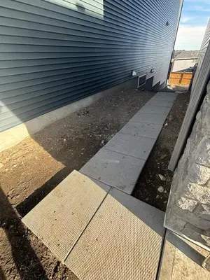 a sidewalk next to a building with a door at Fowler Road Cozy Lower Suite in Airdrie