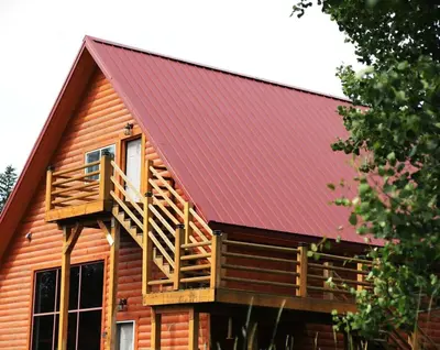 a cabin with a red roof and a deck at Creekside Haven on a Sleddog Farm in Dovercourt