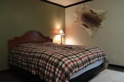a bedroom with a bed with a plaid blanket and a lamp at Creekside Haven on a Sleddog Farm in Dovercourt