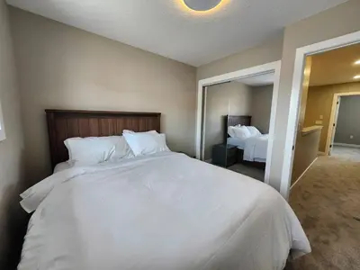 a bedroom with a large white bed and a mirror at Harmony Haven in Drumheller in Drumheller