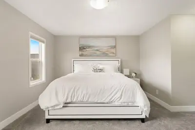 a bedroom with a bed with a white bedspread at A beautiful home in Airdrie in Airdrie