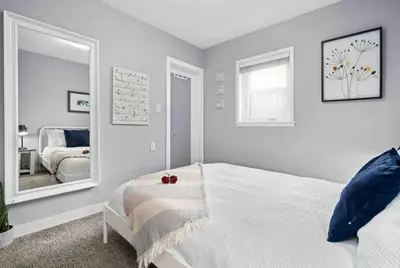 a bedroom with a white bed and a mirror at Bright and Open Coziness. 10 minutes to Stampede in Calgary