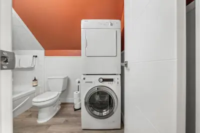 a bathroom with a washing machine and a toilet at Mid Century Zen Suite. 1 BR. Near DT, C-train. in Calgary