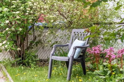 a chair sitting in the grass near some flowers at Mid Century Zen Suite. 1 BR. Near DT, C-train. in Calgary