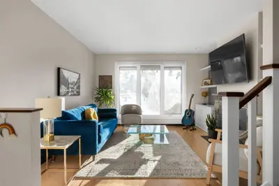 a living room with a blue couch and a window at Bright and Welcoming Mount Pleasant Home, near DT in Calgary
