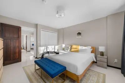 a bedroom with a large bed and a blue bench at Bright and Welcoming Mount Pleasant Home, near DT in Calgary