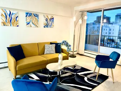 a living room with a yellow couch and blue chairs at Cool and Cozy 17th Ave Nest in Calgary
