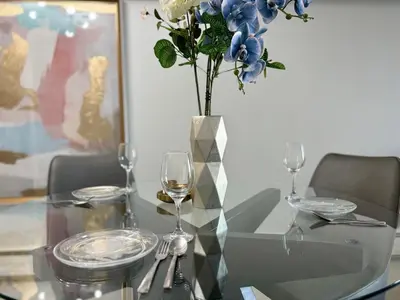 a glass table with a vase with blue and white flowers at Cool and Cozy 17th Ave Nest in Calgary