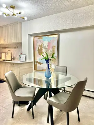 a glass dining room table with chairs and a vase with flowers at Cool and Cozy 17th Ave Nest in Calgary