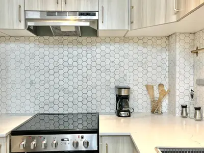 a kitchen with white hexagonal tiles on the wall at Cool and Cozy 17th Ave Nest in Calgary