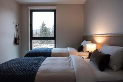 two beds in a room with a window at Luna Ridge - Thoughtfully Designed 3-Bedroom Condo in Revelstoke