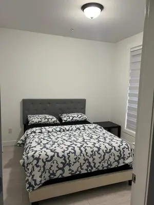 a bedroom with a bed with a black and white comforter at 2 Bedroom plus den 2 Bathroom apartment in Surrey