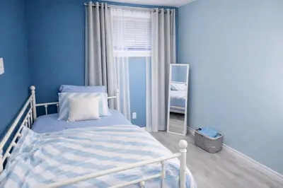 a bedroom with blue walls and a bed with a mirror at Home Basement, Friendly Family in Calgary