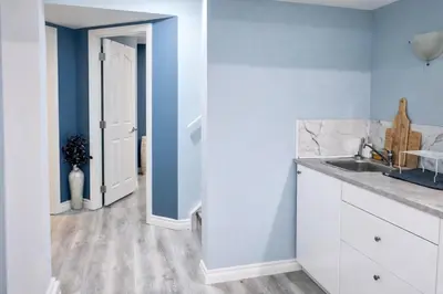 a white kitchen with a sink and a door at Home Basement, Friendly Family in Calgary