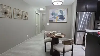 a kitchen with a table and chairs and a refrigerator at SkyHaven Urban Condo near YYC Airport in Calgary