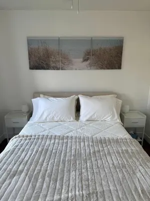 a bed with white sheets and a picture of a beach at Private 1BR, AC, Strong Wi-Fi, Netflix and Amazon Prime in Victoria