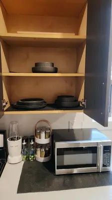 a microwave in a kitchen with plates and dishes at Hebzibah's Luxe in Prince George