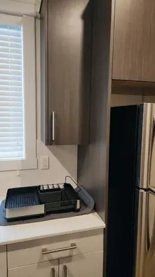 a kitchen with a counter with a sink and a refrigerator at Hebzibah's Luxe in Prince George